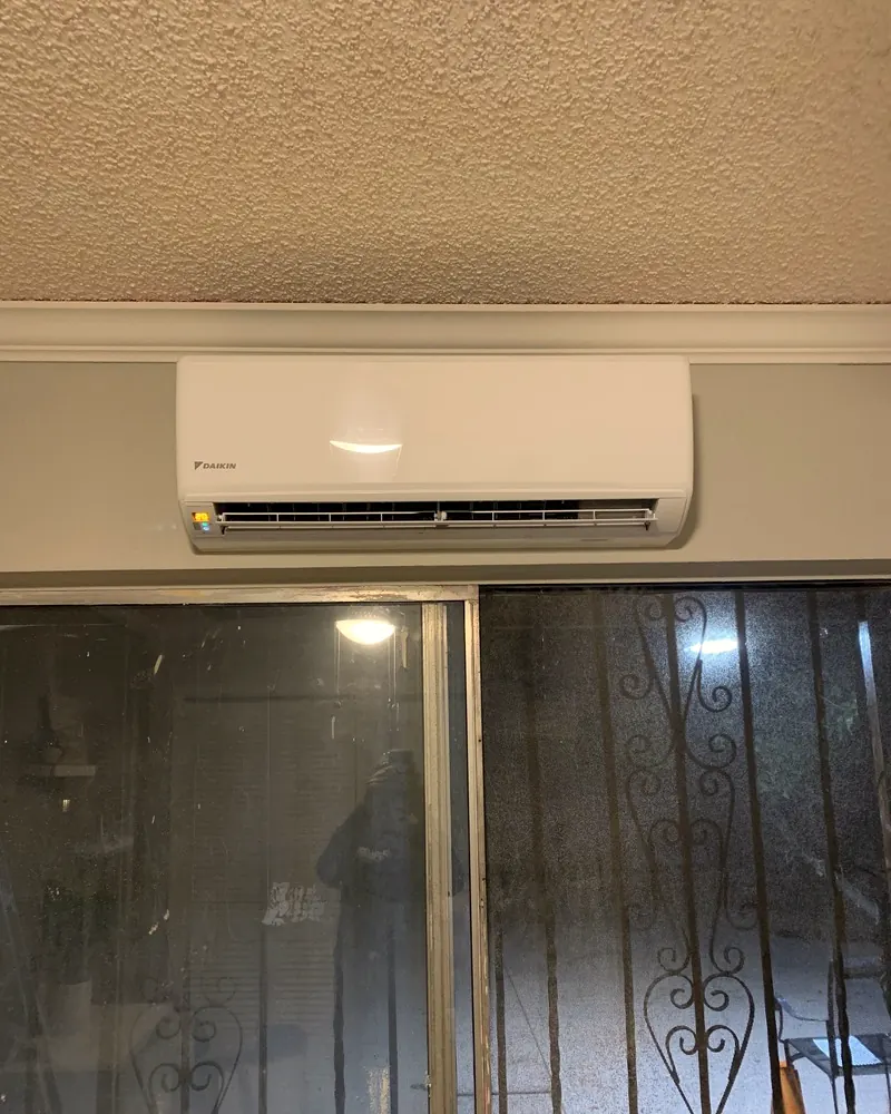 Ductless mini-split indoor unit mounted on the wall above a sliding glass door
