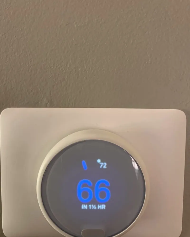 Nest smart thermostat on a wall, set to 66 degrees